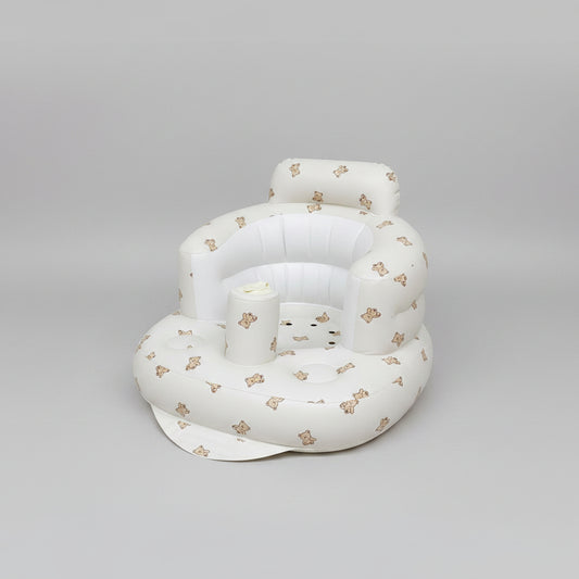 White inflatable baby seat with teddy bear patterns on a soft surface